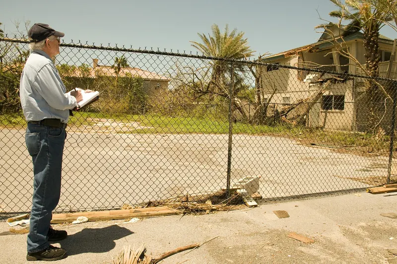 Housing damage inspector with a clipboard examining a storm-damaged property in Texas