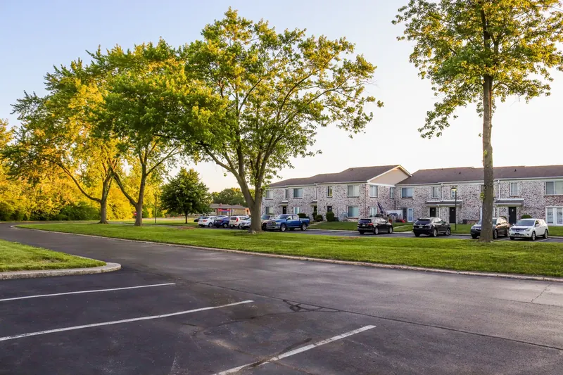Two-story apartment complex buildings with a tree-lined parking lot
